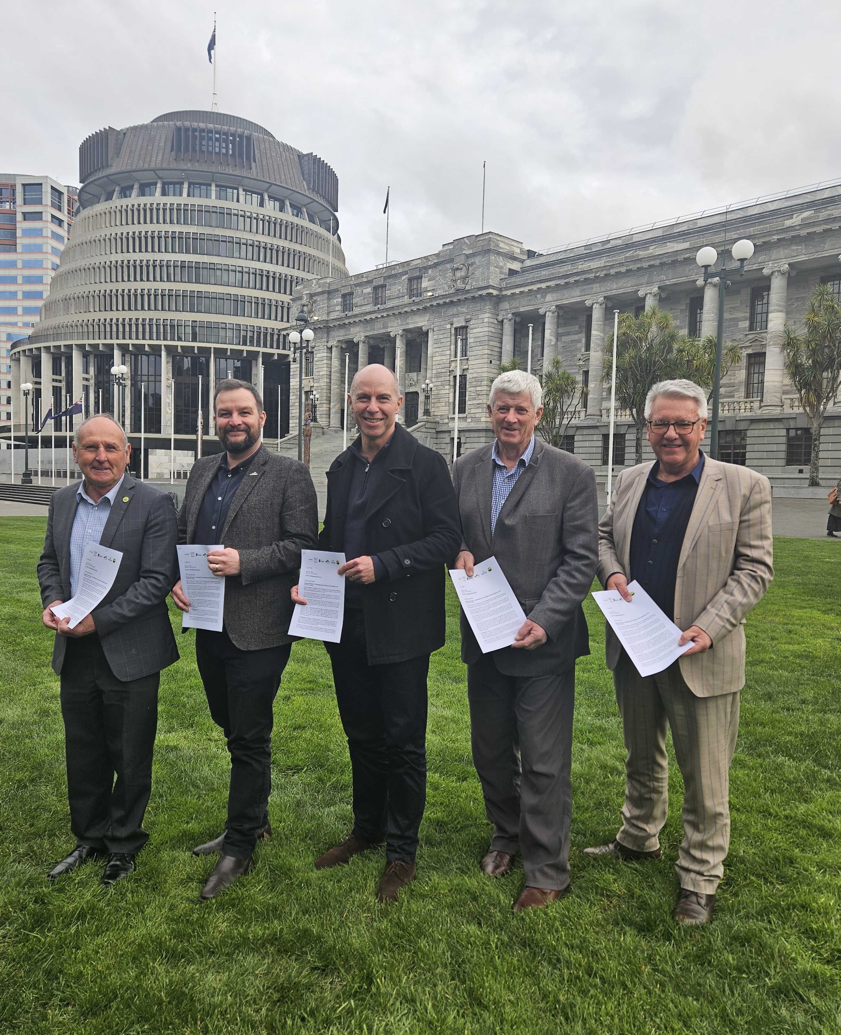 Mayors of the five districts standing outside the Beehive in Wellington. Each mayor is holding a signed copy of the Memorandum.